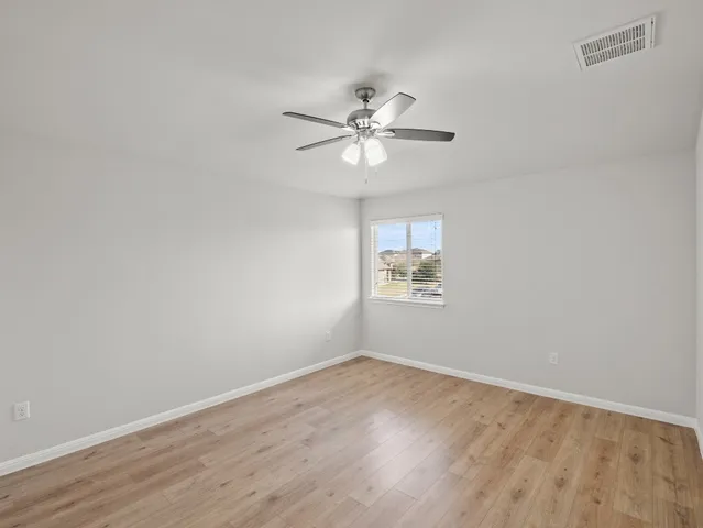 a view of a room with wooden floor and a ceiling fan