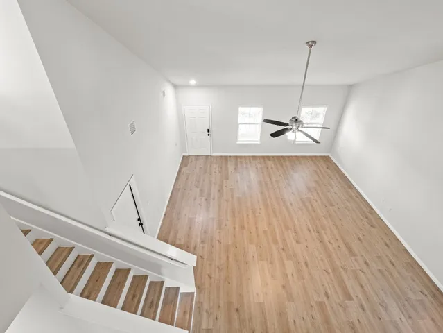 a view of a room with wooden floor and ceiling fan