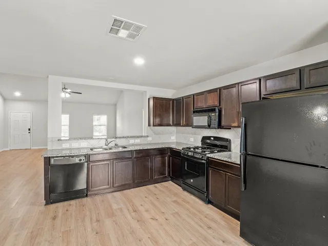 a kitchen with stainless steel appliances granite countertop a sink stove and refrigerator