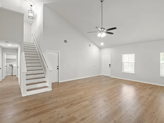 an empty room with wooden floor ceiling fan and window