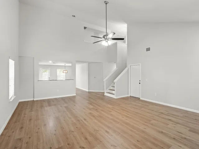 a view of empty room with wooden floor and ceiling fan