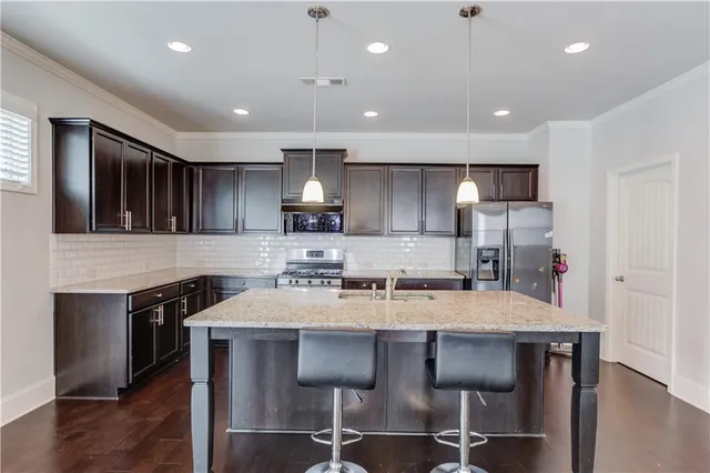 a kitchen with refrigerator a sink and chairs