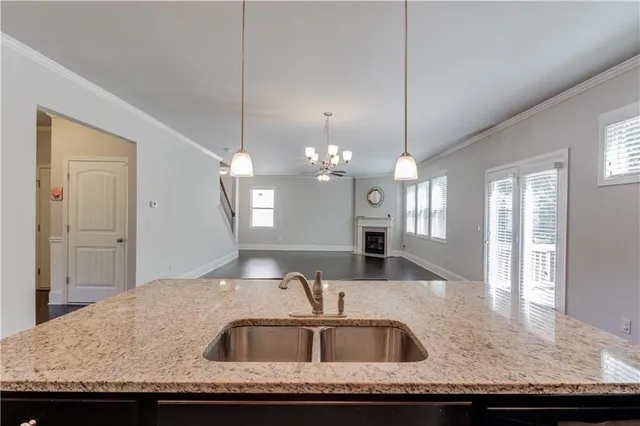a kitchen with kitchen island granite countertop a sink a counter top space and living room view