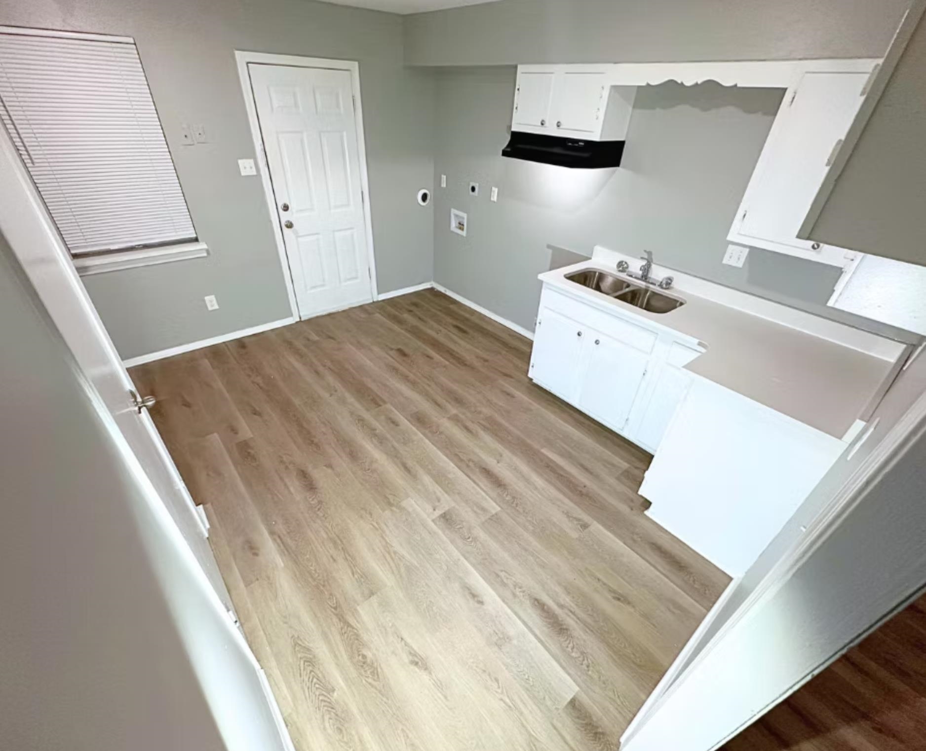Kitchen featuring baseboards, light countertops, light wood-style flooring, white cabinets, and a sink