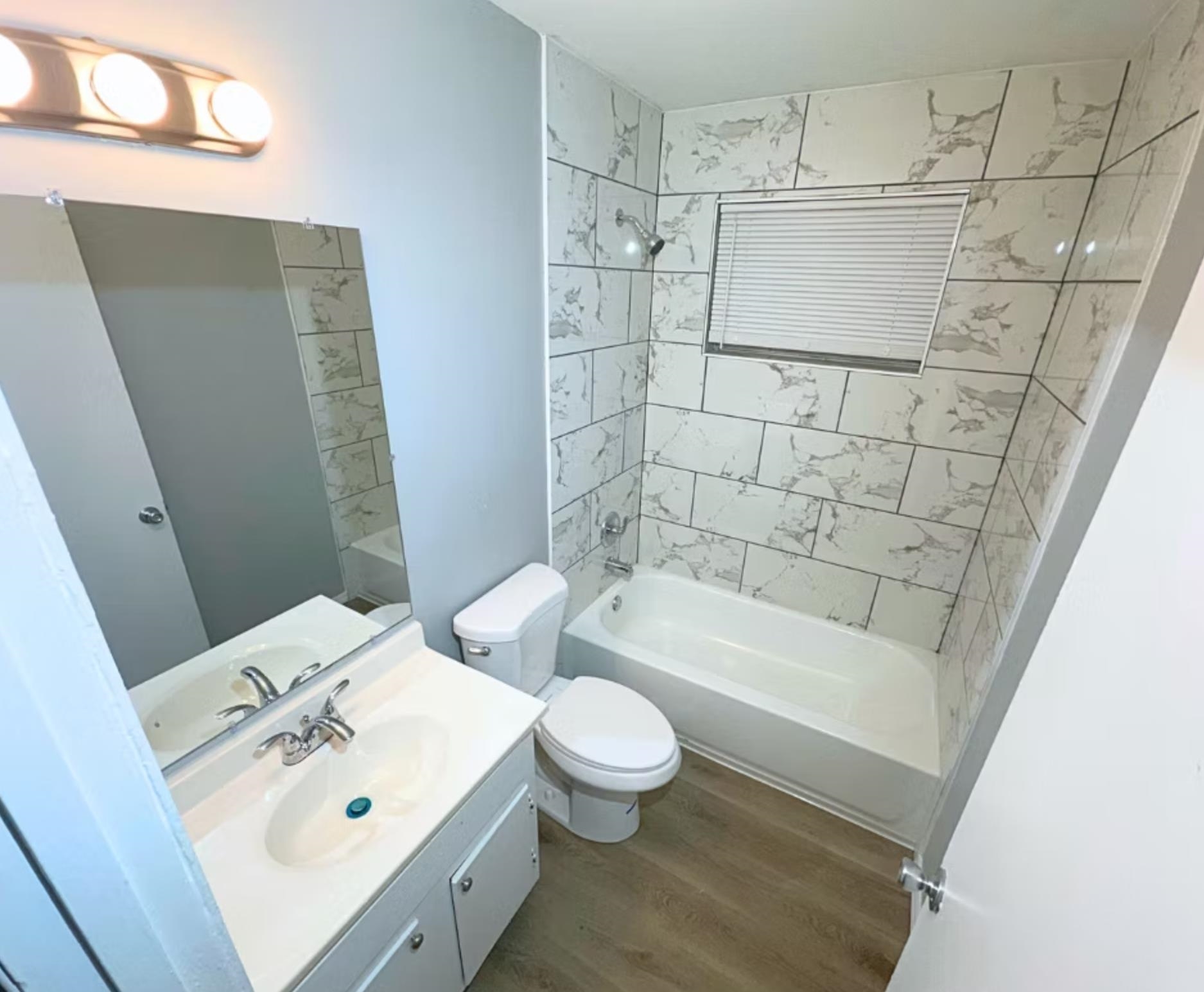 Full bath with vanity, shower / tub combination, toilet, and wood finished floors