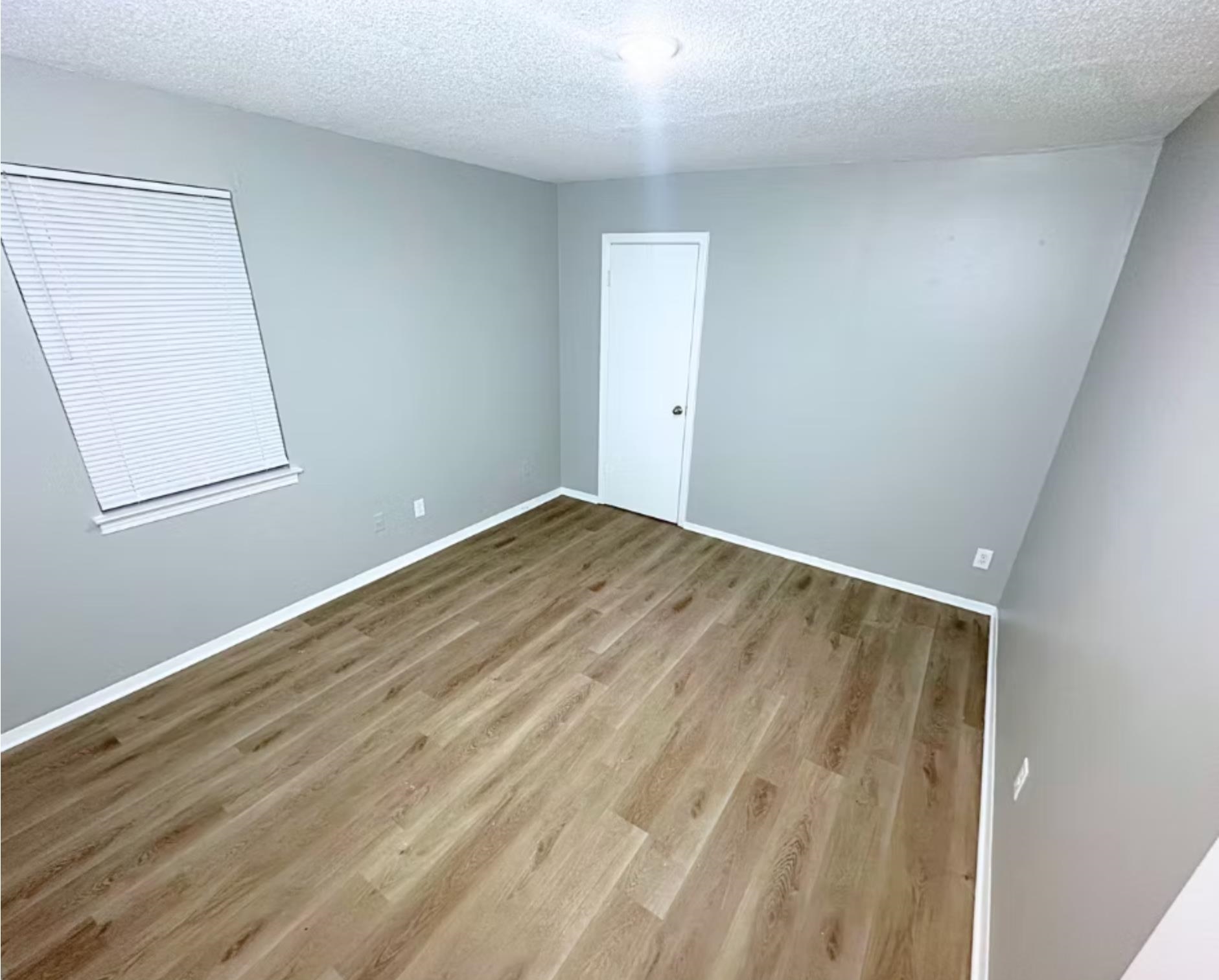 Unfurnished room with baseboards, a textured ceiling, and wood finished floors