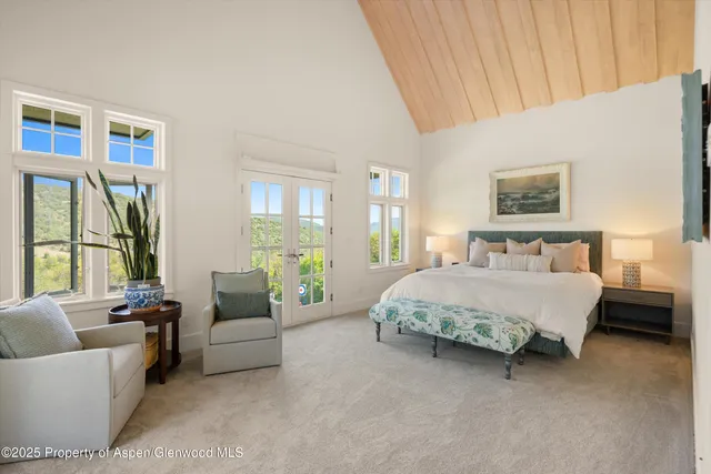 a spacious bedroom with a bed and glass window