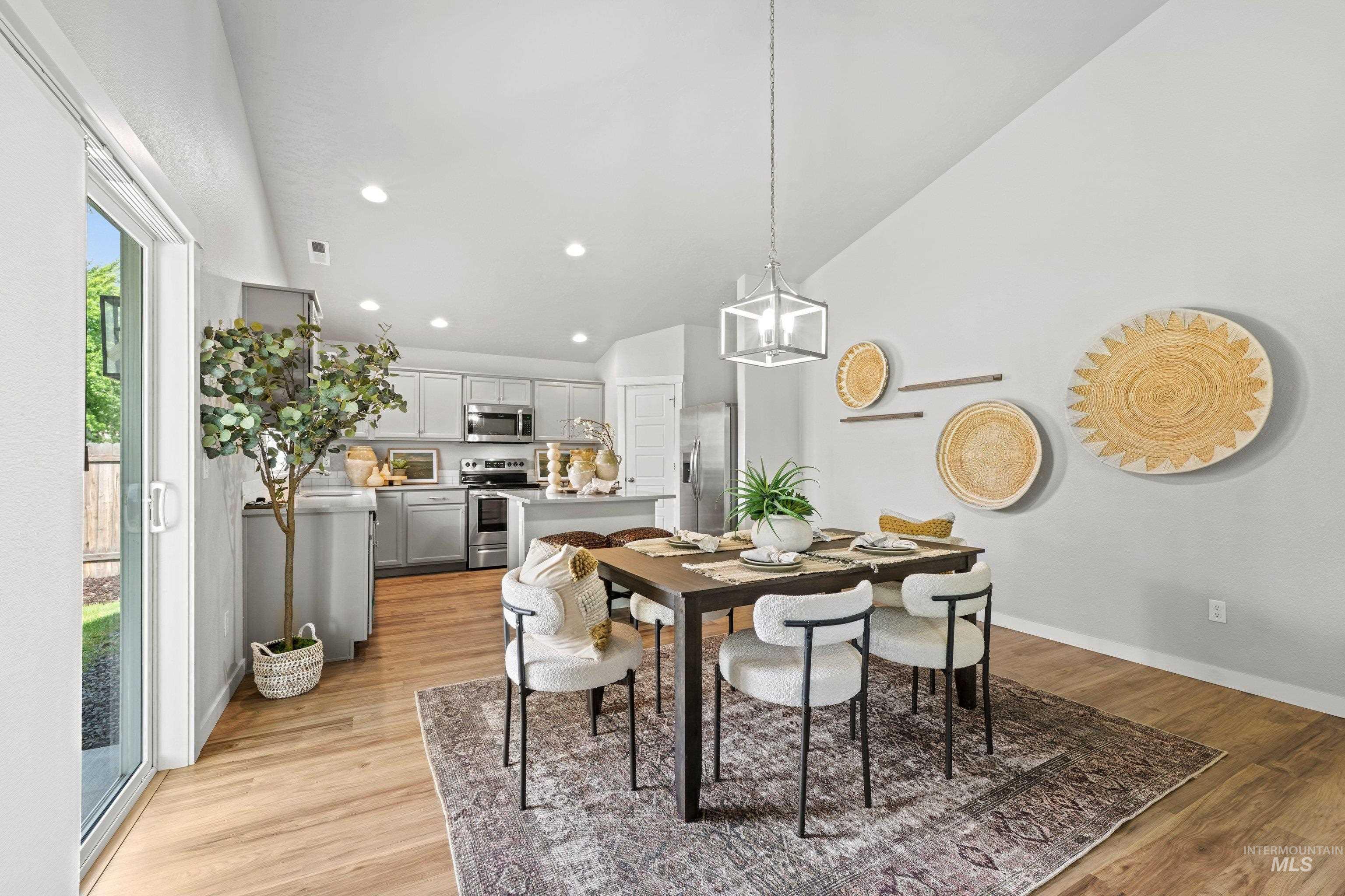12744 West Fig Street Boise, ID 83713 - Photo 12 of 34 Open-concept dining area featuring vaulted ceilings, wood-finish flooring, and a modern geometric pendant light fixture