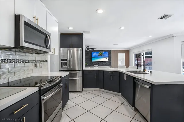a kitchen with stainless steel appliances granite countertop a sink dishwasher stove top oven and refrigerator