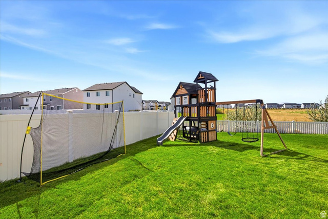3049 South 2675 West Syracuse, UT 84075 - Photo 35 of 37 Expansive backyard featuring a lush lawn, white vinyl fencing, and a multi-level playset with swings