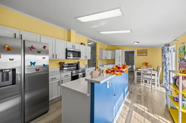 a view of a kitchen with stainless steel appliances kitchen island granite countertop a refrigerator and a dining table with chairs