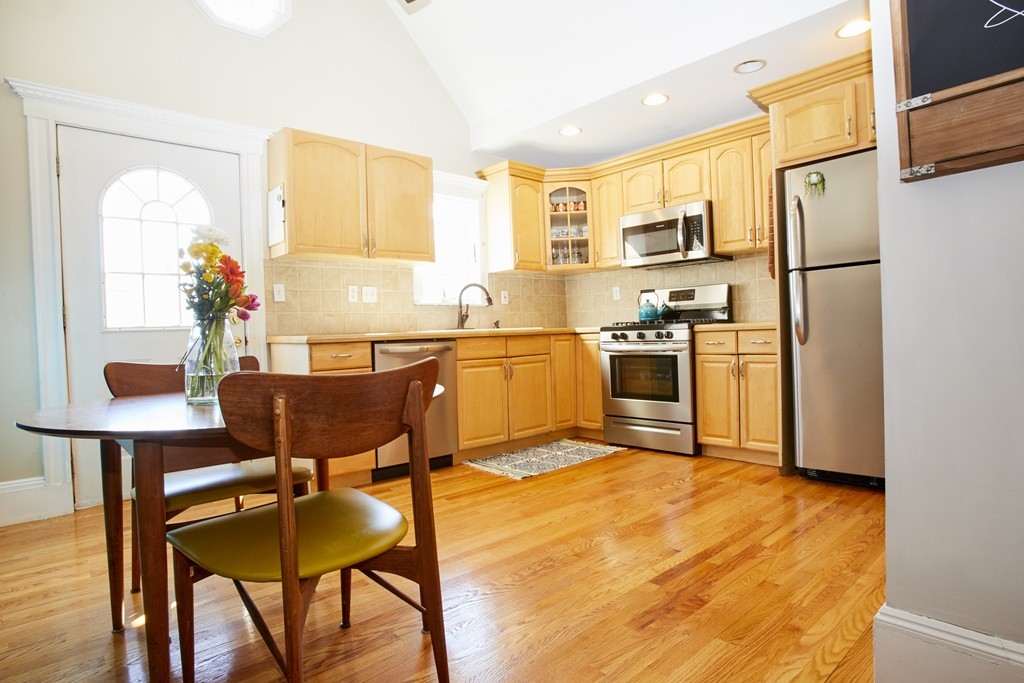 56 Hinckley Street, Unit 2 Somerville, MA 02145 - Photo 7 of 18 a kitchen with a table chairs refrigerator and microwave