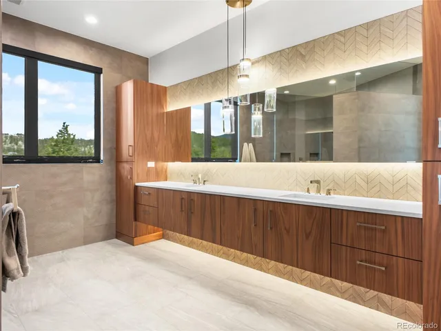 a bathroom with a double vanity sink a large mirror and a bathtub