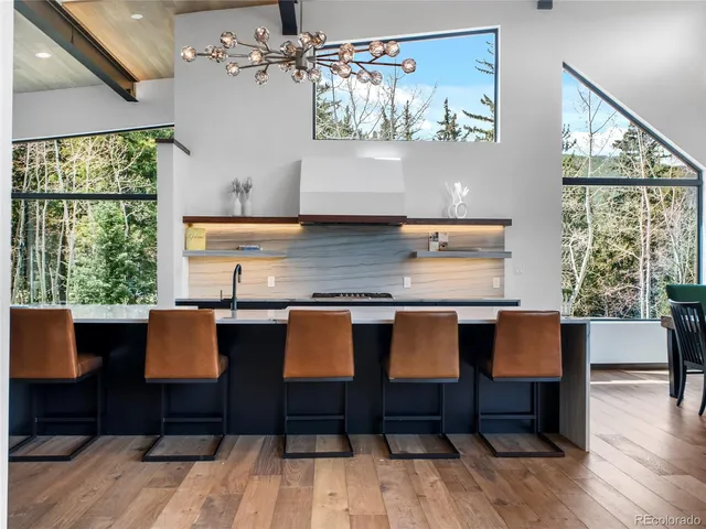 a view of kitchen with stainless steel appliances granite countertop a table chairs stove and wooden floor