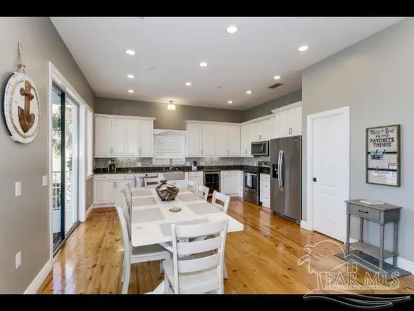 a living room with stainless steel appliances furniture a dining table and kitchen view
