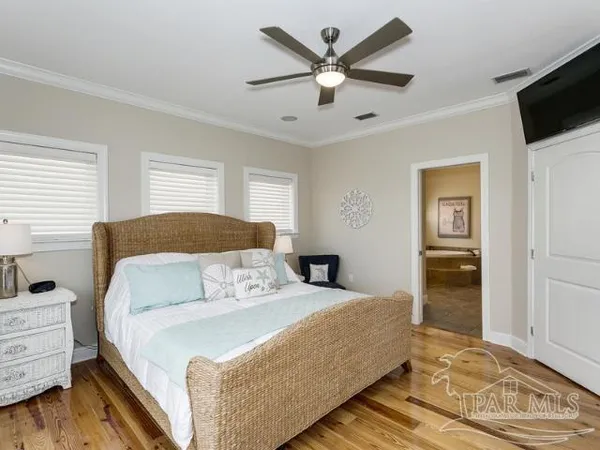 a bedroom with a large bed a flat tv screen and dresser