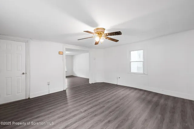 a view of an empty room with window and wooden floor