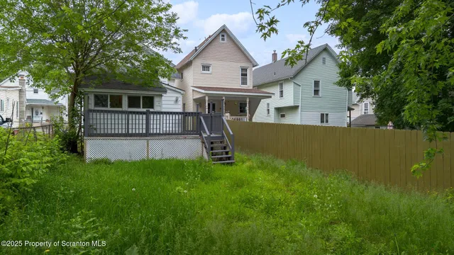 a view of a house with a big yard and large trees