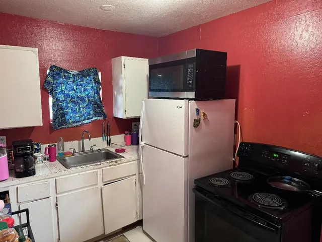 a white refrigerator freezer and a stove sitting inside of a kitchen