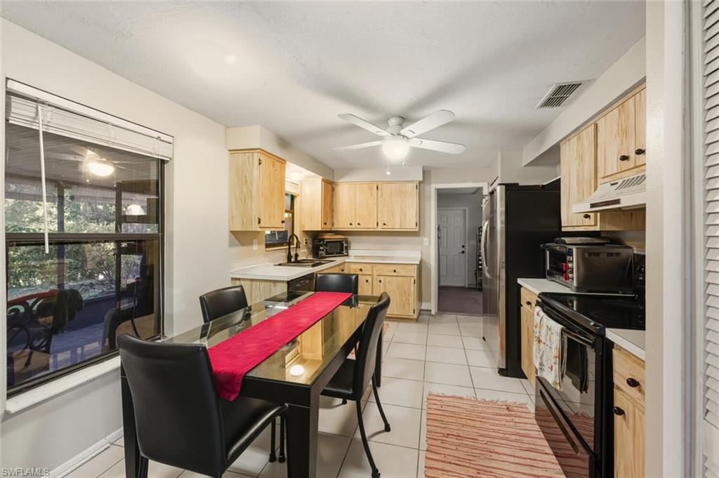 2747 47th Street Southwest Naples, FL 34116 - Photo 7 of 21 a kitchen with stainless steel appliances kitchen island granite countertop a dining table chairs refrigerator and sink