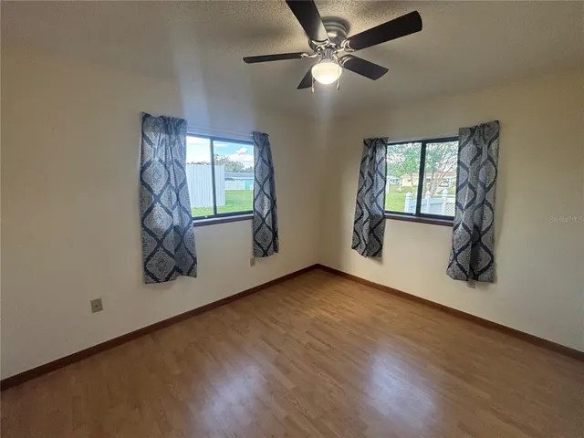 an empty room with windows and ceiling fan