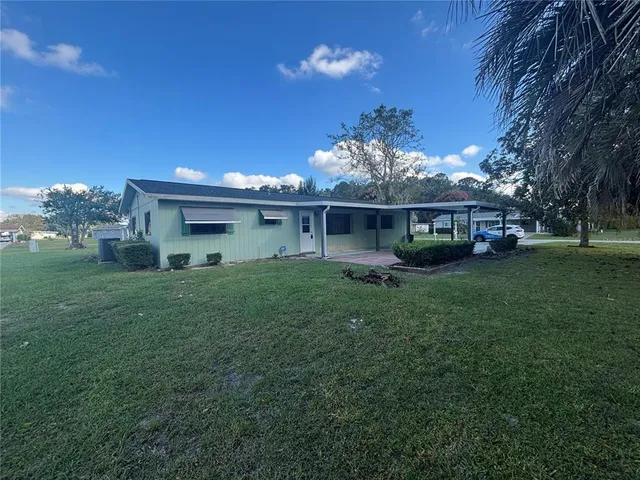 a view of a house with a big yard potted plants and large tree