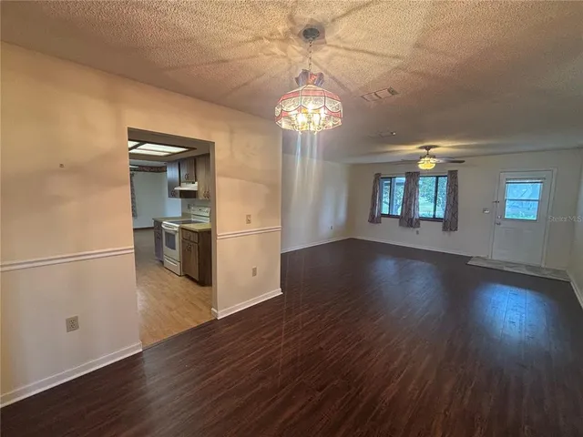 a view of a kitchen with a refrigerator a stove top oven and wooden floor
