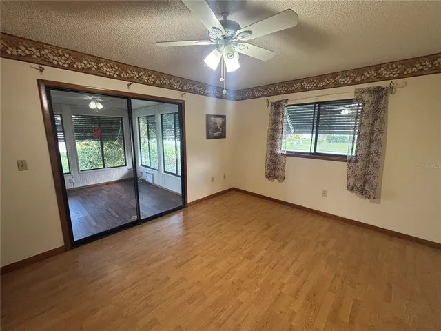 en empty room with a chandelier fan and windows