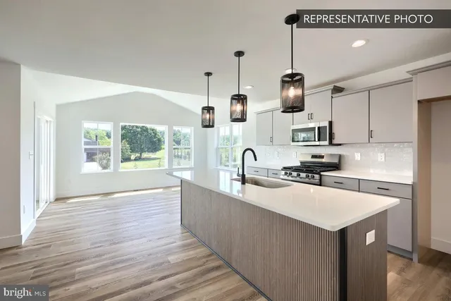 a kitchen with stainless steel appliances a sink stove and wooden floor