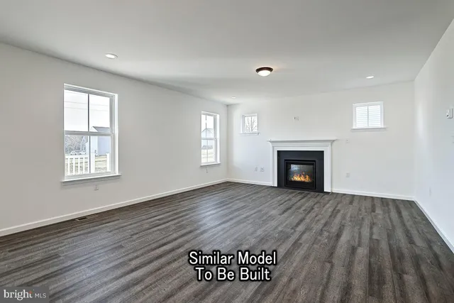 a view of an empty room with wooden floor and windows