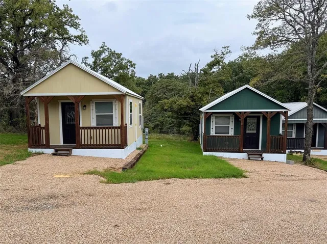 a view of a house with a yard and large trees