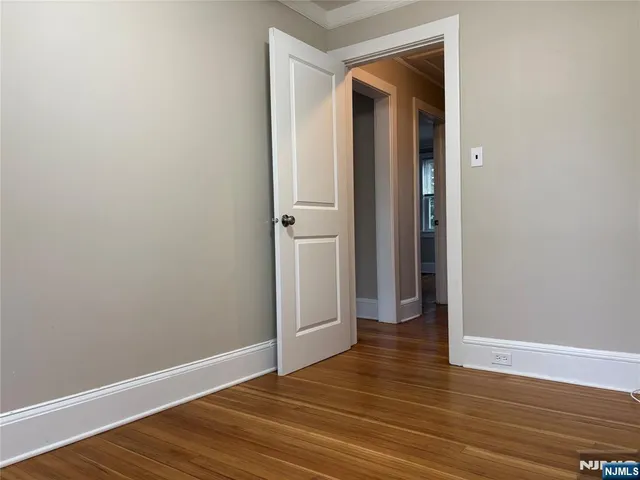 a view of an empty room with wooden floor and closet