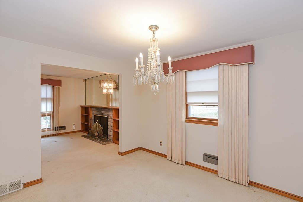 209 3rd Street Stoughton, MA 02072 - Photo 10 of 36 a view of a livingroom with a fireplace a chandelier and windows