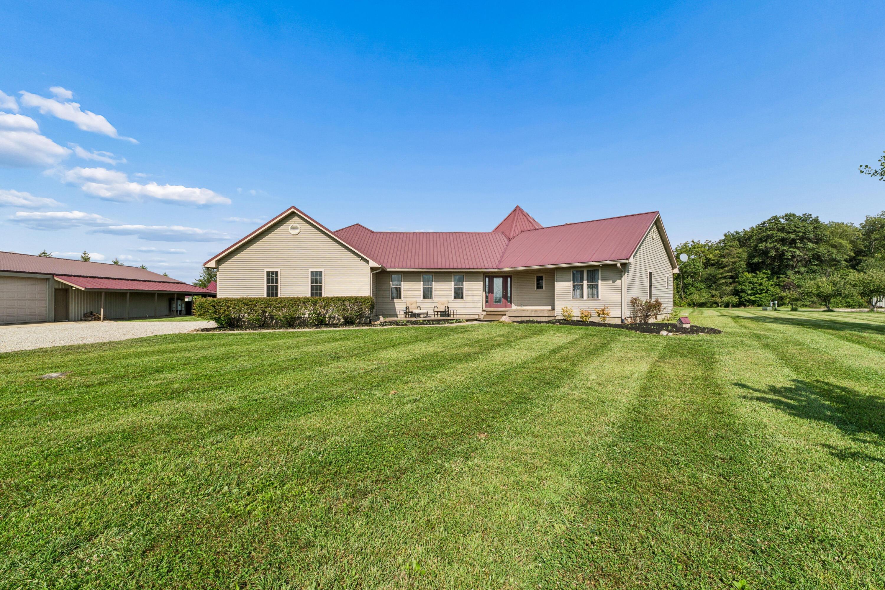 18964 London Road Circleville, OH 43113 - Photo 4 of 57 Expansive green lawn, Clay siding exterior, burgundy metal roof, covered front entry, and detached garage