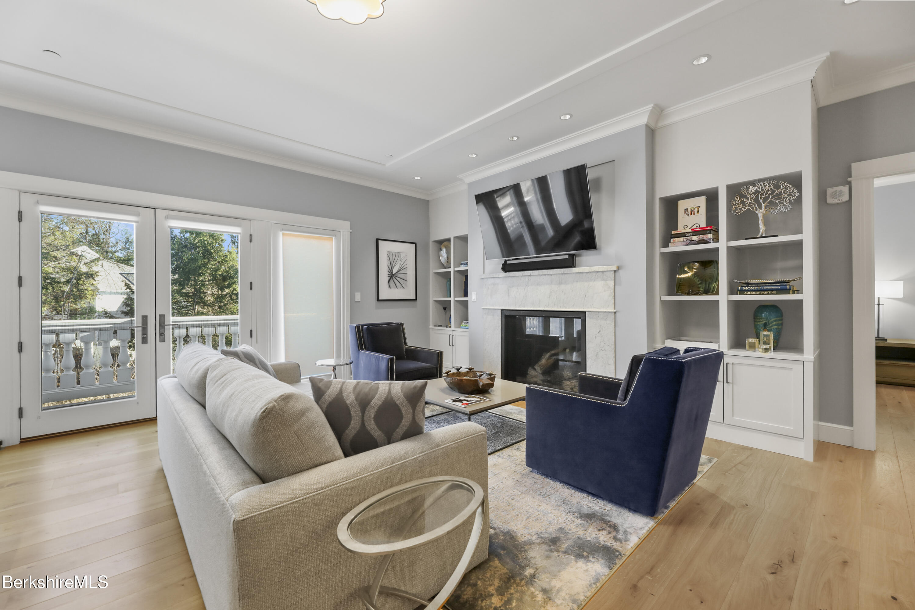 a living room with furniture a fireplace a flat screen tv and windows