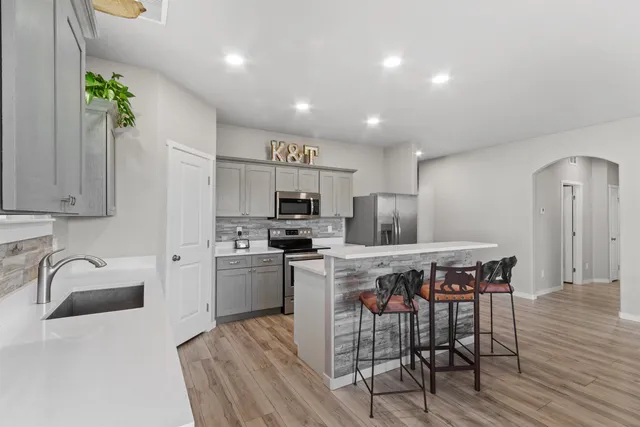 a kitchen with stainless steel appliances granite countertop a kitchen island hardwood floor sink and stove