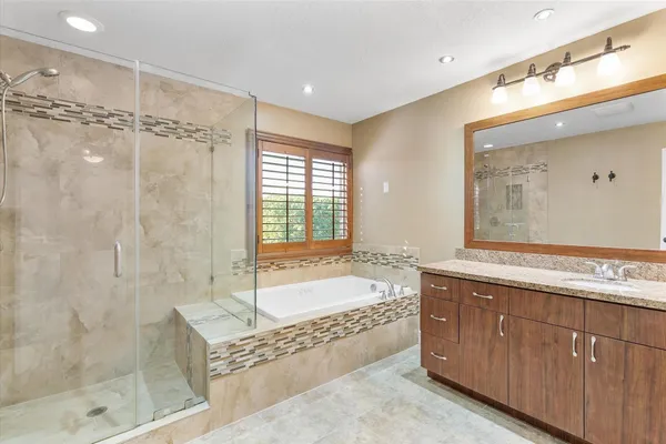 a spacious bathroom with a granite countertop tub sink shower and mirror