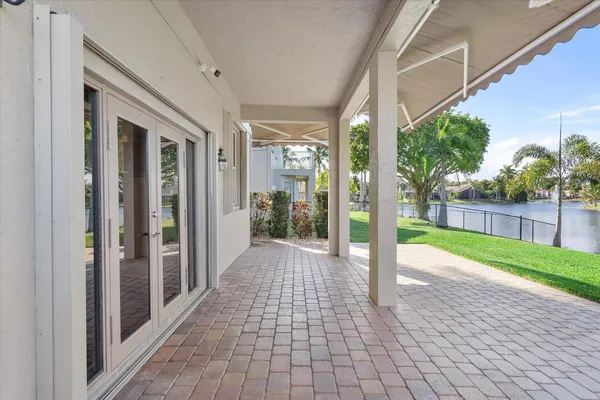 a view of a white house with a big yard and potted plants