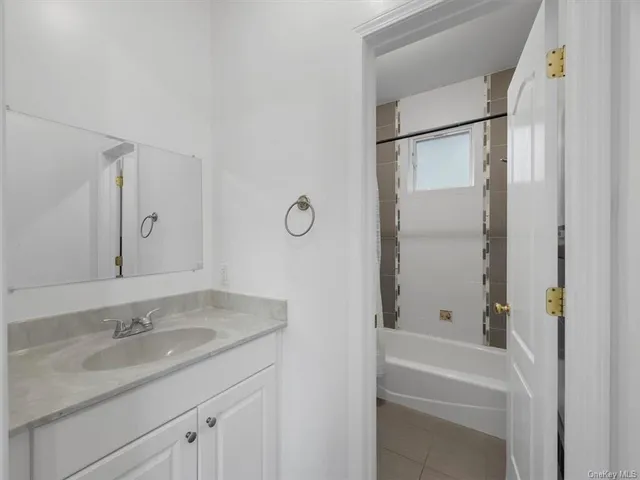 a bathroom with a granite countertop sink mirror toilet and bathtub