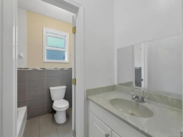 a bathroom with a granite countertop toilet sink and mirror