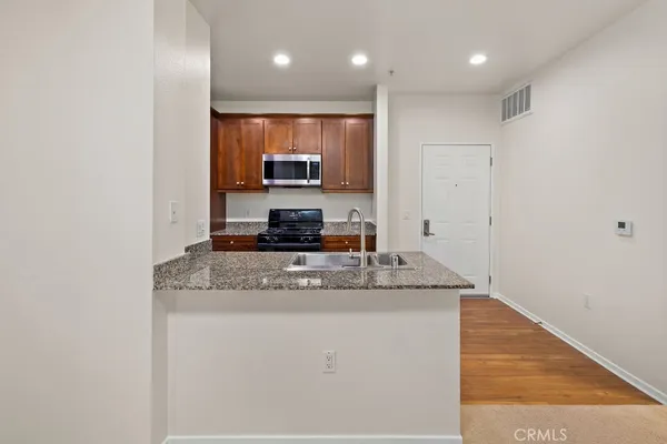 a kitchen with stainless steel appliances granite countertop a sink a stove and a refrigerator