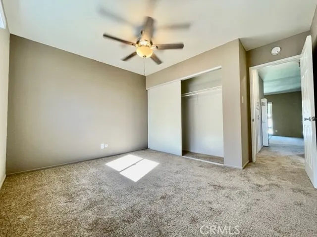 an empty room with a chandelier fan and closet