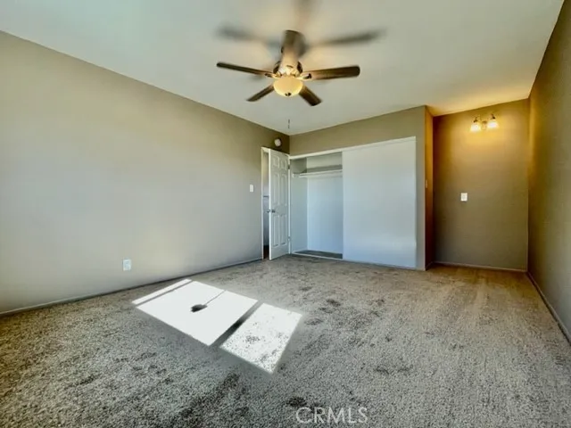 an empty room with a ceiling fan and window