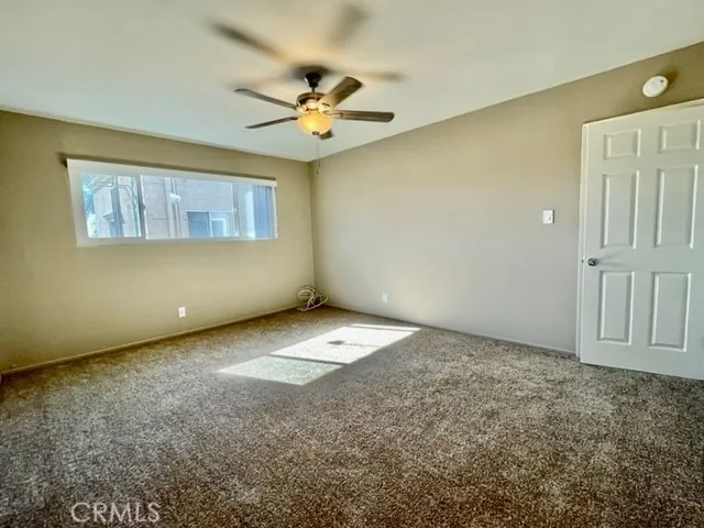 an empty room with a ceiling fan and window
