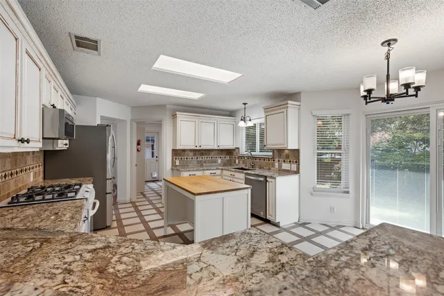 a kitchen with stainless steel appliances kitchen island granite countertop a refrigerator and a stove top oven