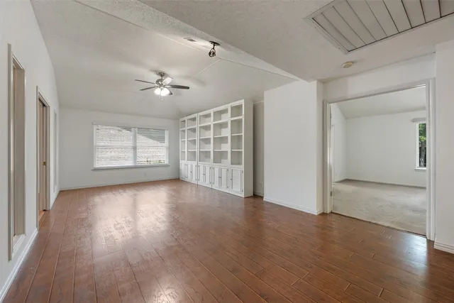 a view of an empty room with a window and wooden floor