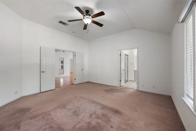 an empty room with fan and windows