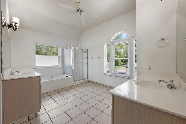 a spacious bathroom with a tub sink and mirror