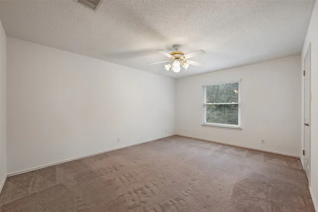 an empty room with a ceiling fan and window