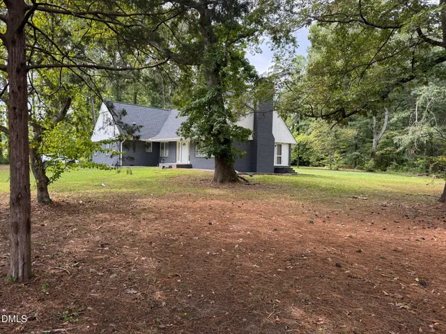 a view of a house with a yard and large trees